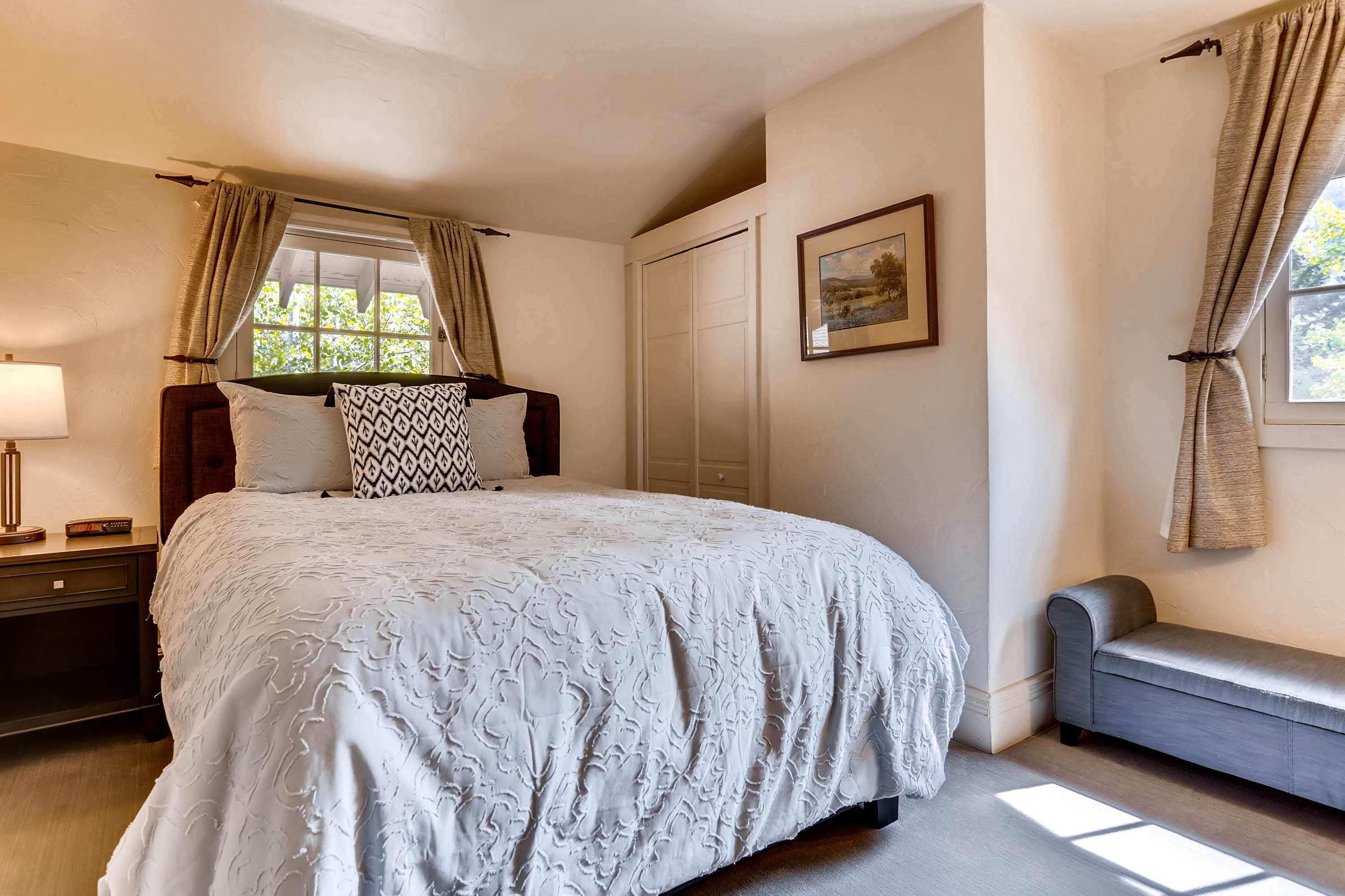 image Sunlit bedroom with soft hues, elegant drapes, and cozy seating, creating a serene and welcoming space.