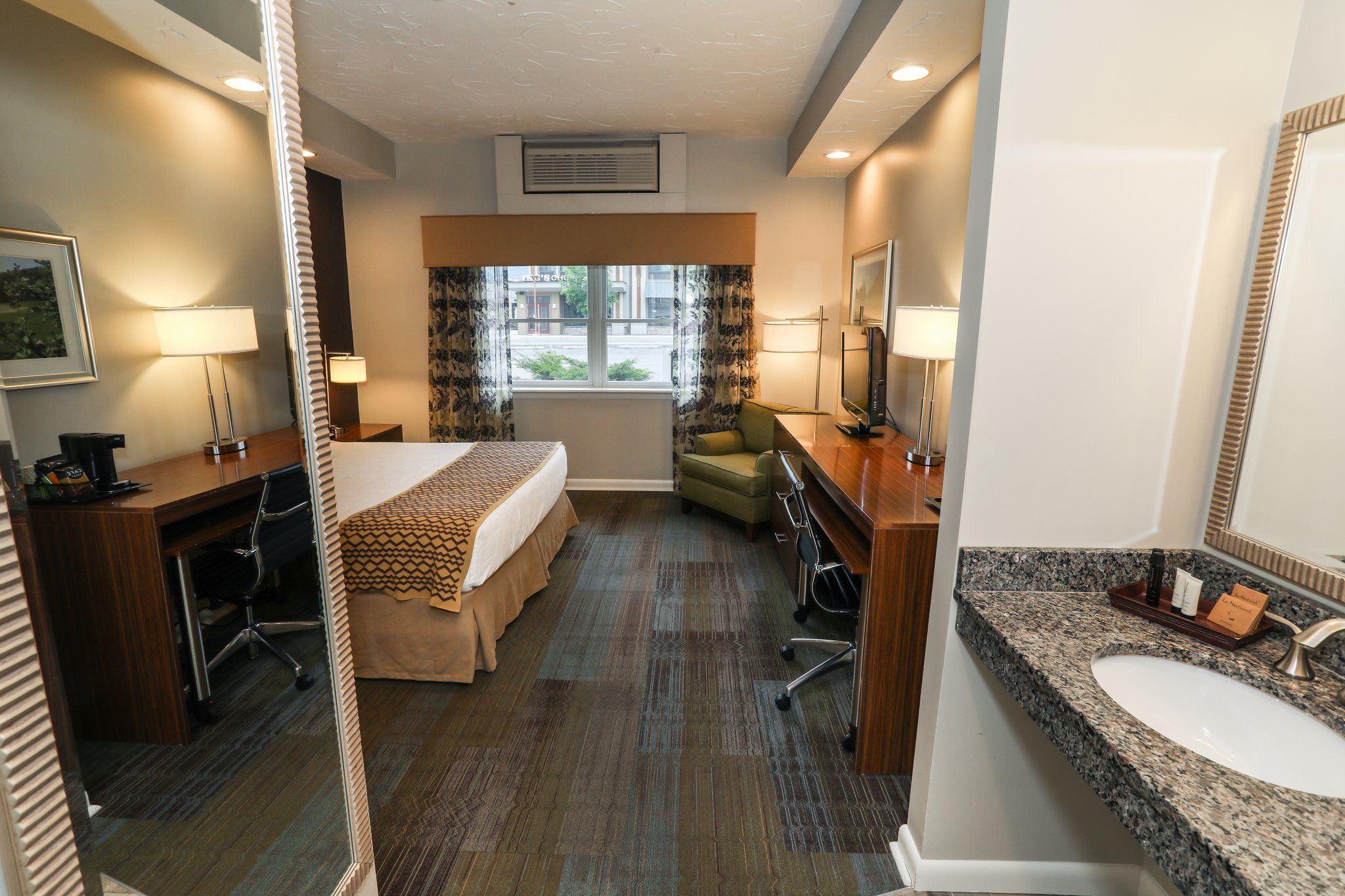 image Well-appointed room featuring a cozy bed, seating area, and convenient workspace.
