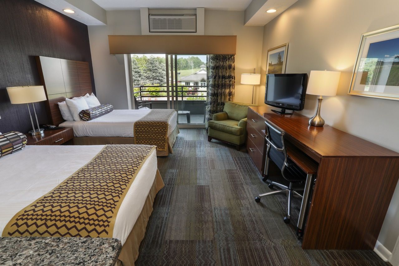 image Spacious room with two beds, a seating area, and convenient workspace, ideal for work or leisure.