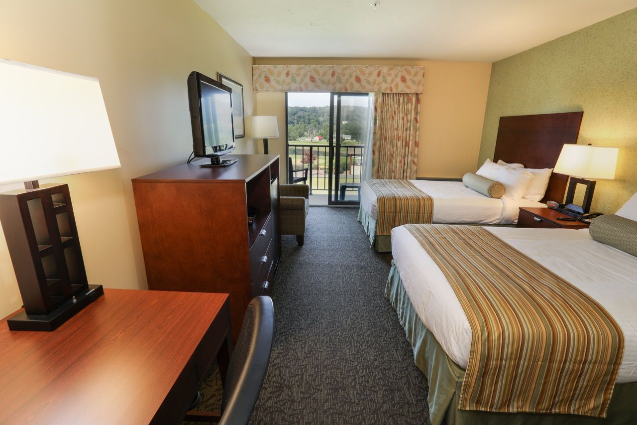 image Cozy guest room with a comfortable bed, flat-screen TV, and balcony access for a relaxing stay.