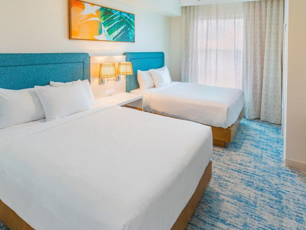 image Spacious room with two plush beds, vibrant décor, and plenty of natural light for a comfortable stay.