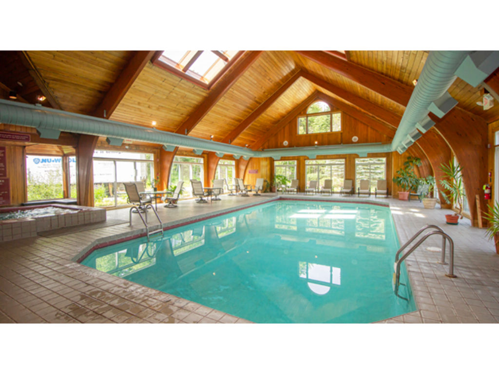 image Spacious indoor pool with vaulted ceilings and large windows, offering a perfect spot for leisure and relaxation.