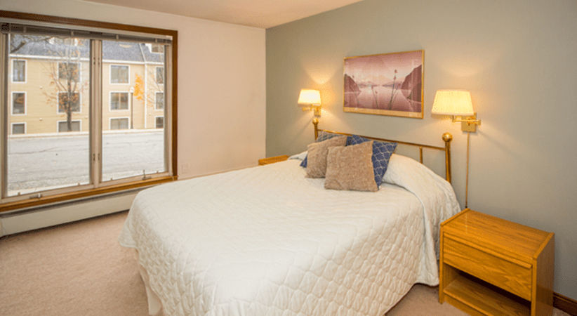 image This serene bedroom offers a comfortable queen-sized bed flanked by bedside lamps, with natural light streaming in from a large window.
