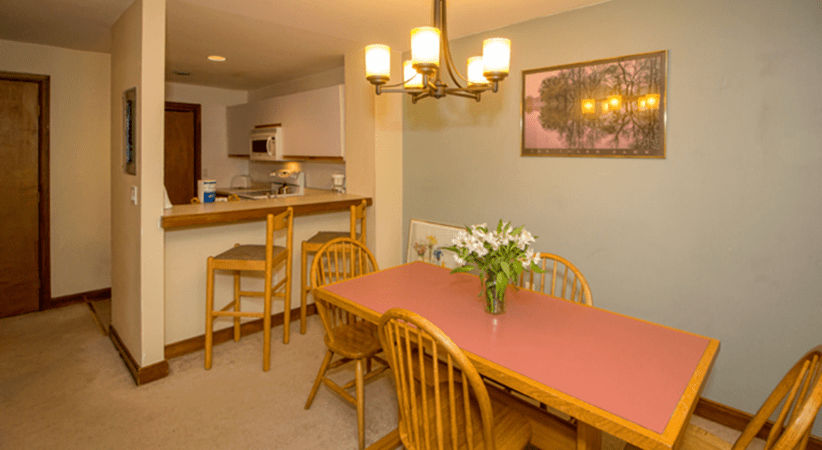 image The dining area showcases a charming wooden table set with fresh flowers, seamlessly integrated with the open kitchen in a warm, inviting space.
