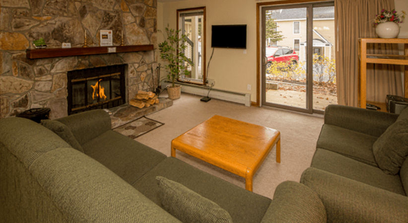 image The inviting living room features a cozy stone fireplace surrounded by soft seating and a view of the outdoors through sliding glass doors.