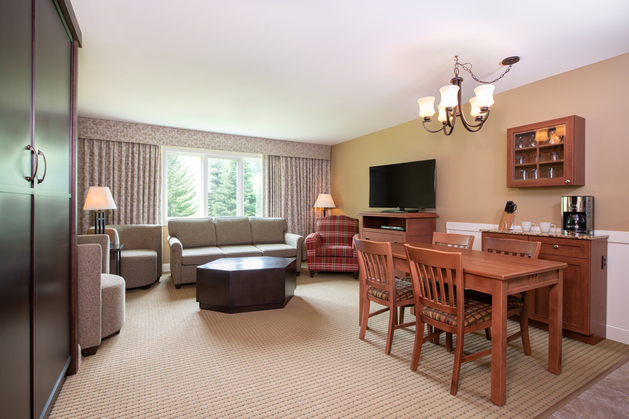 image Spacious living and dining area with a cozy fireplace and large windows, perfect for gathering and enjoying the natural light.