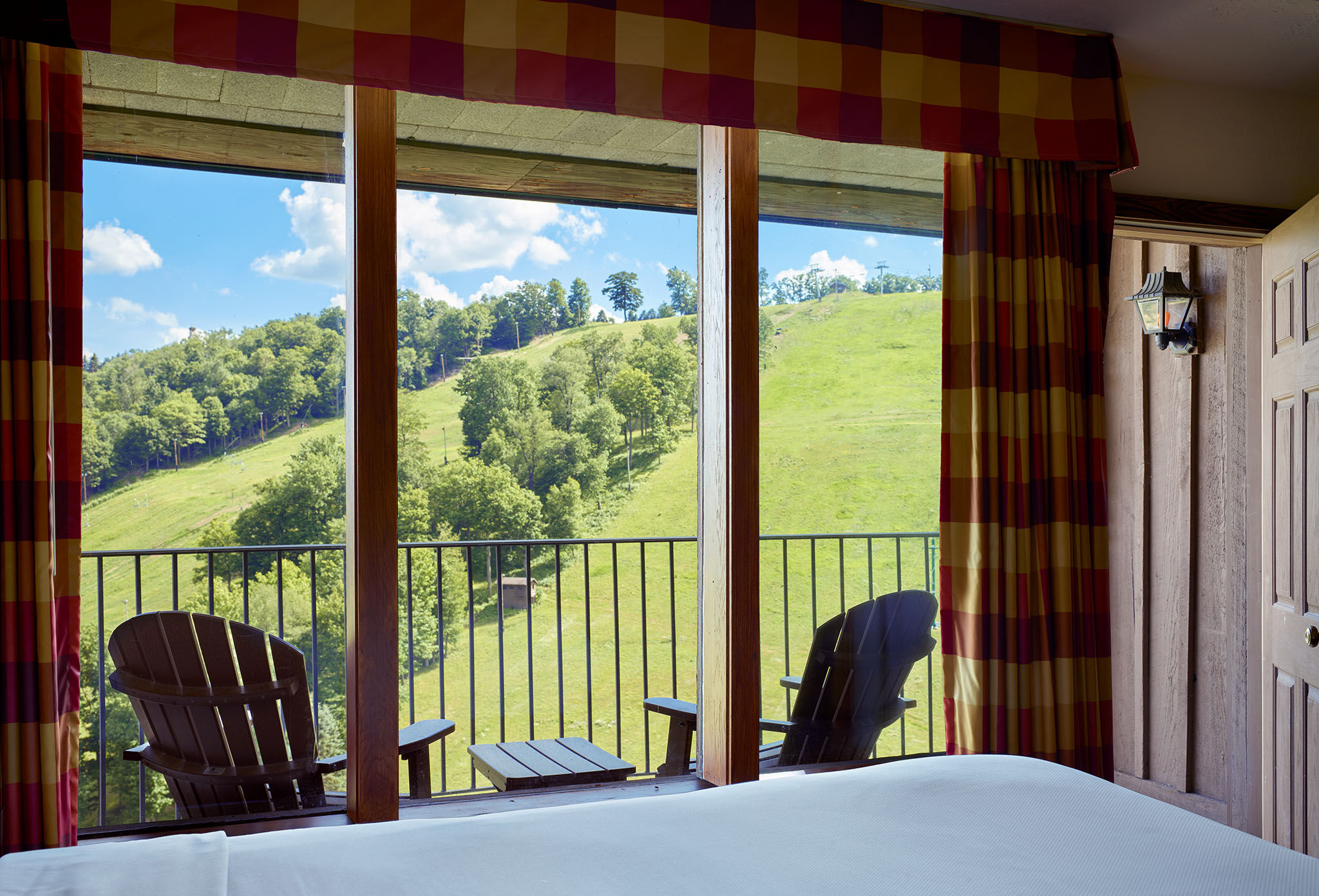 image Scenic bedroom with floor-to-ceiling windows and a private balcony overlooking picturesque landscapes.