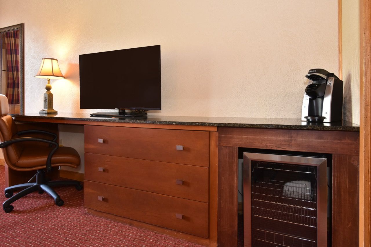 image Functional workspace with a sleek desk, flat-screen TV, and a convenient coffee station for a comfortable stay.