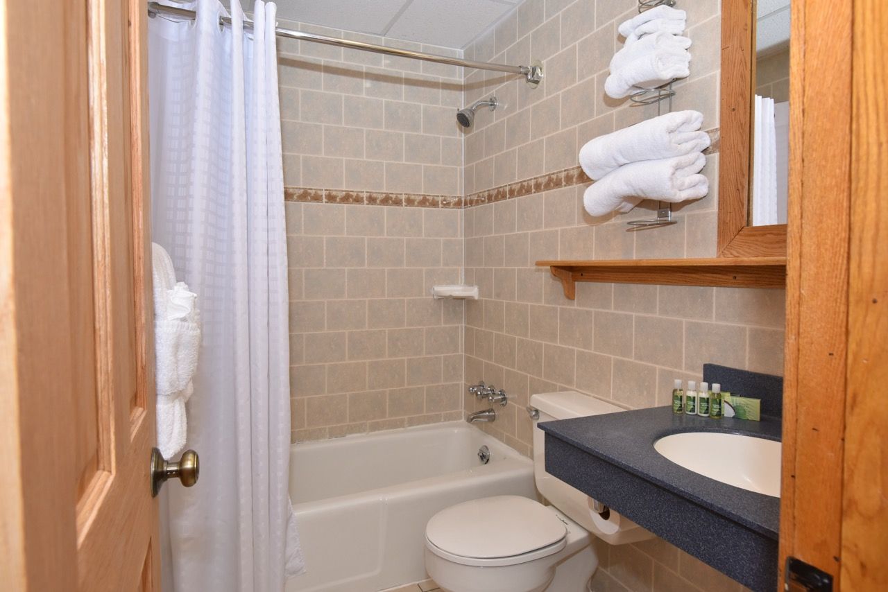 image Pristine bathroom with a tiled shower-tub combination, ample towels, and thoughtful storage for added convenience.