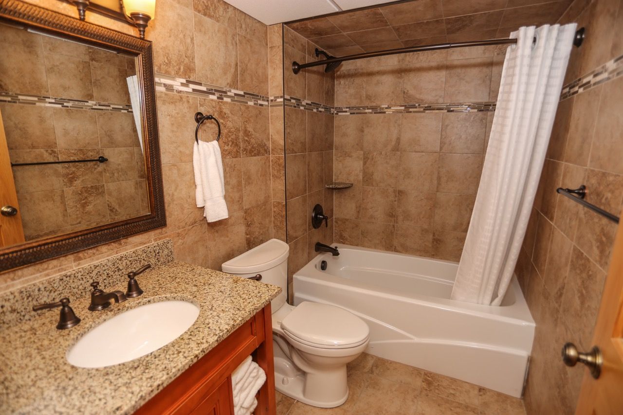 image Beautifully designed bathroom with stone tiles, a spacious vanity, and a relaxing shower-tub combination.