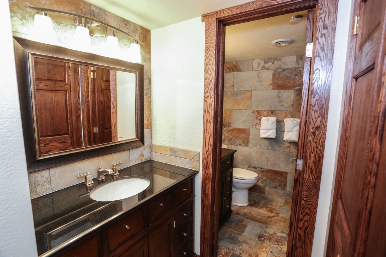 image Elegant bathroom with rich wood cabinetry, a spacious vanity, and a stone-tiled shower for a rustic yet refined touch.