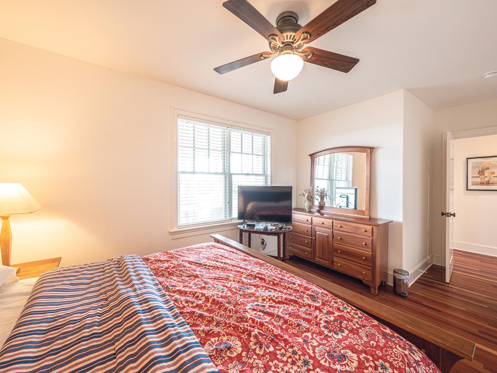 image Spacious master bedroom with a king-sized bed, hardwood floors, and ample natural light for a peaceful night’s sleep.