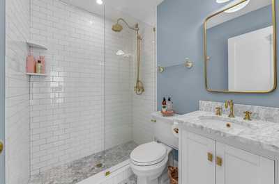 Modern full bathroom with a spacious walk-in shower, marble finishes, and gold fixtures for a spa-like feel.