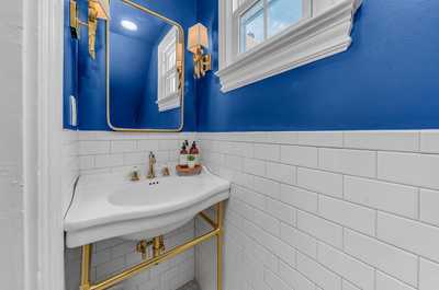 Elegant half-bathroom with a vibrant blue wall and gold fixtures, adding a touch of luxury.