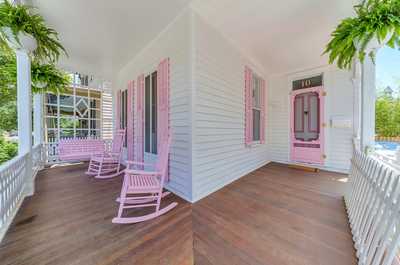 Charming wraparound porch with cozy pink rocking chairs, ideal for sipping morning coffee or enjoying the sunset.