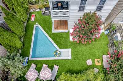 Private backyard oasis featuring a heated pool, sun loungers, and lush greenery for a serene outdoor escape.