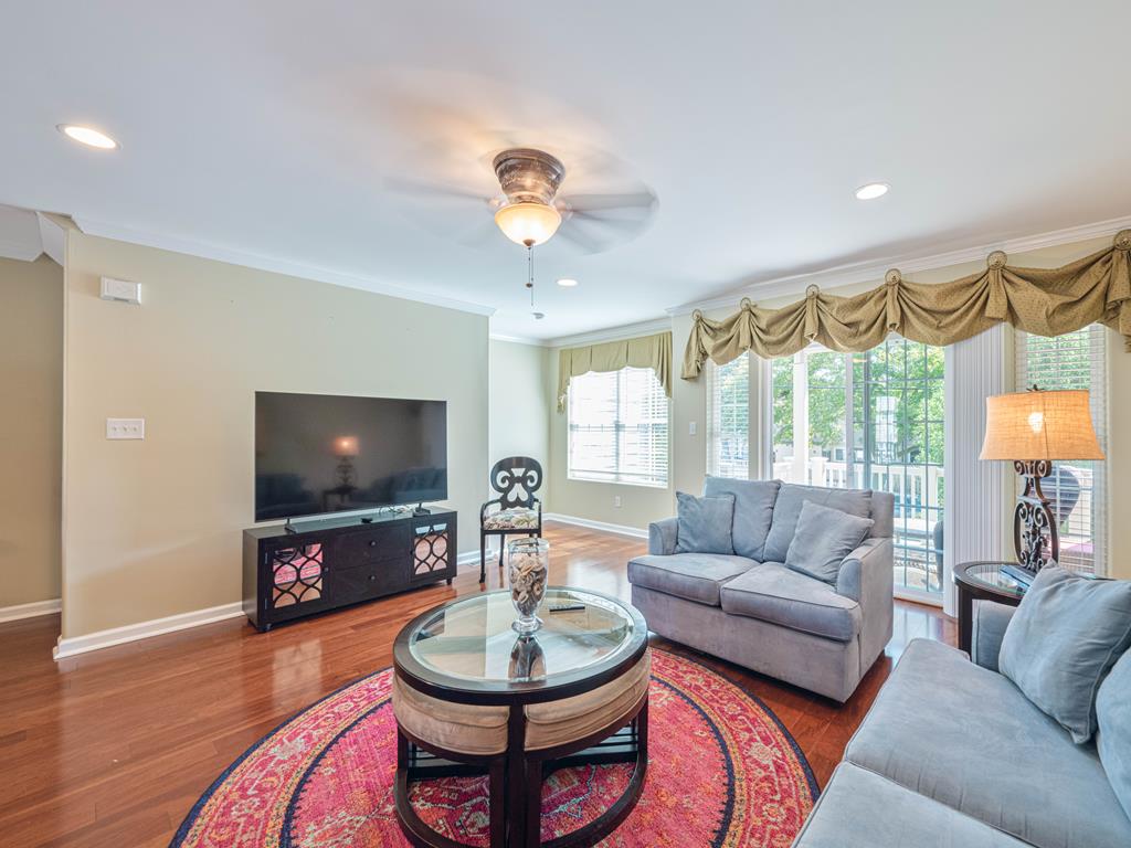 image Large living room with stylish decor, ceiling fans, and expansive windows for an abundance of natural light.