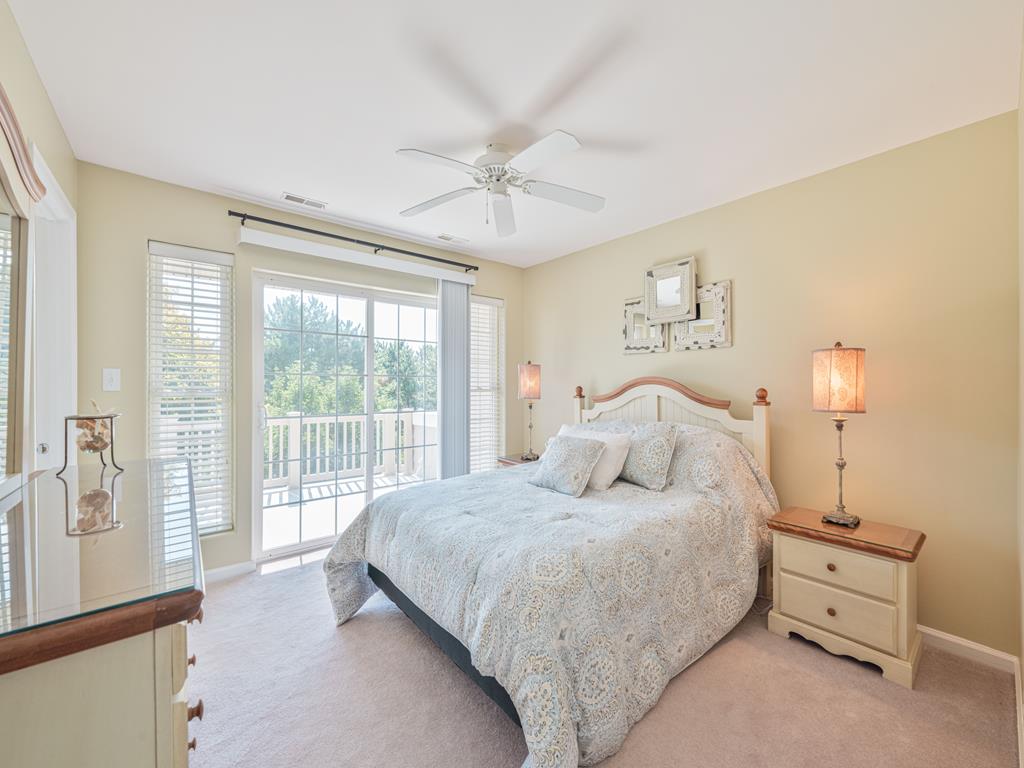 image Elegant bedroom with balcony access, a ceiling fan, and plush bedding for your comfort.