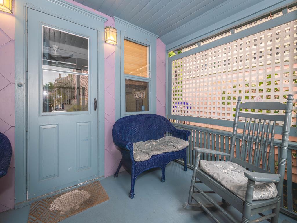 image Cozy front porch with a classic rocking chair and cushioned bench, creating the perfect spot to relax after a day exploring town.