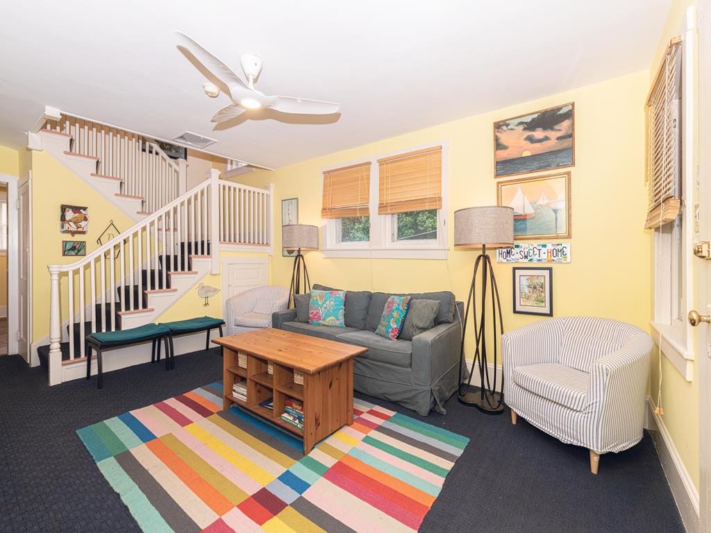 image Another view of the living area showcasing the open layout, modern ceiling fan, and staircase leading to the upper level.