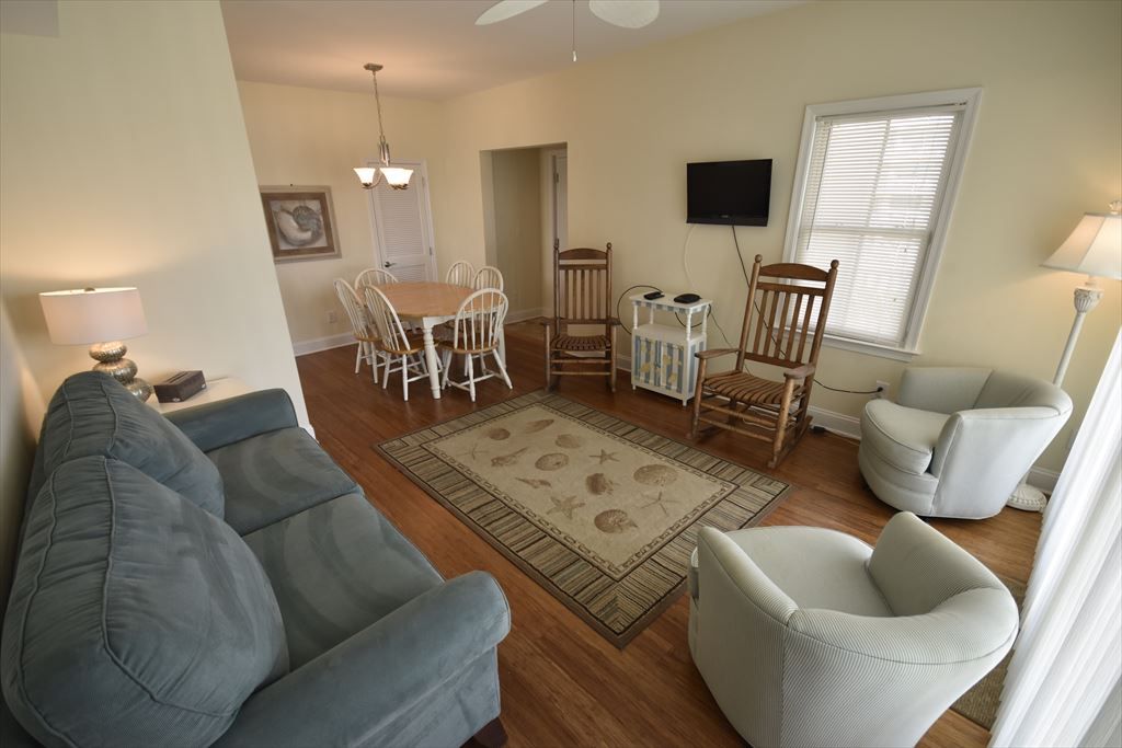 image Spacious living room featuring cozy furnishings, a flat-screen TV, and ample natural light for relaxing after a beach day.