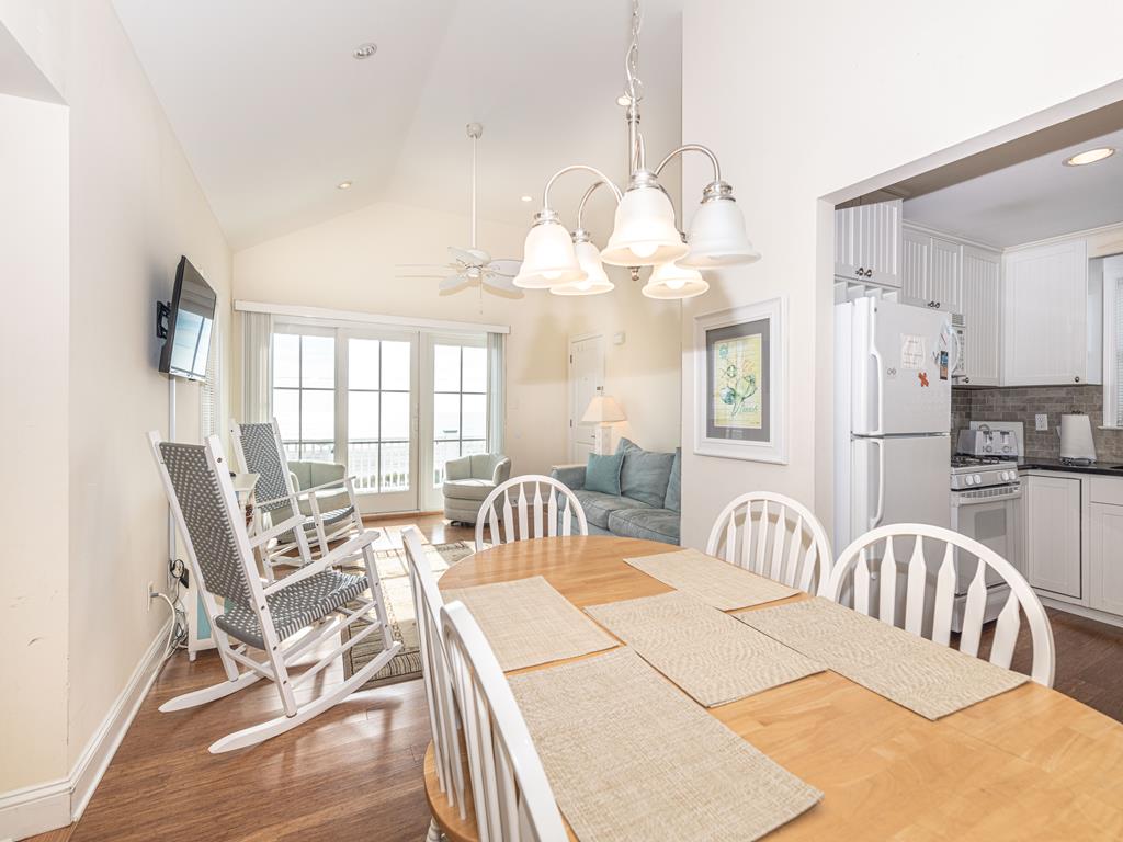 image Bright open-concept dining and living area featuring coastal décor, comfortable seating, and large windows that fill the space with natural light and ocean views.