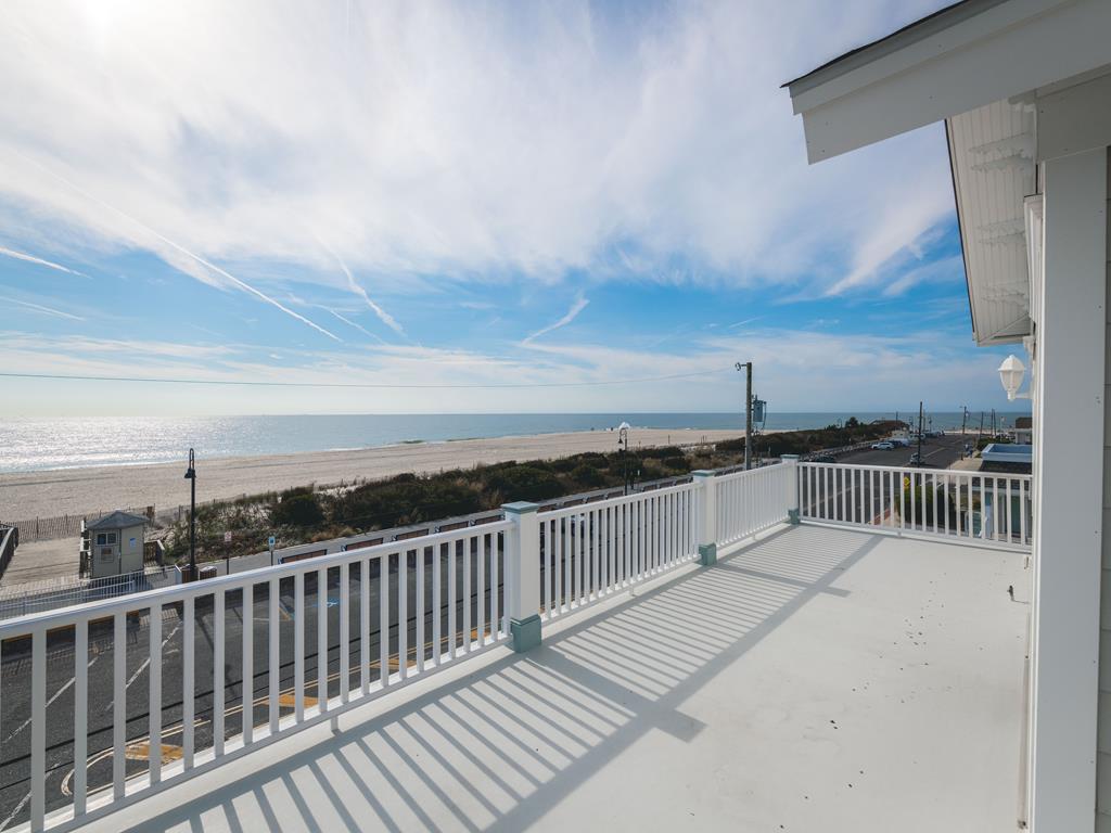 image A breathtaking ocean view from the condo's spacious deck, where the shimmering waves meet the sandy beach under a bright blue sky.