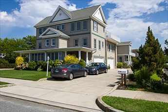 image Stunning three-story house with a modern design, ample parking, and a beautifully landscaped front yard.
