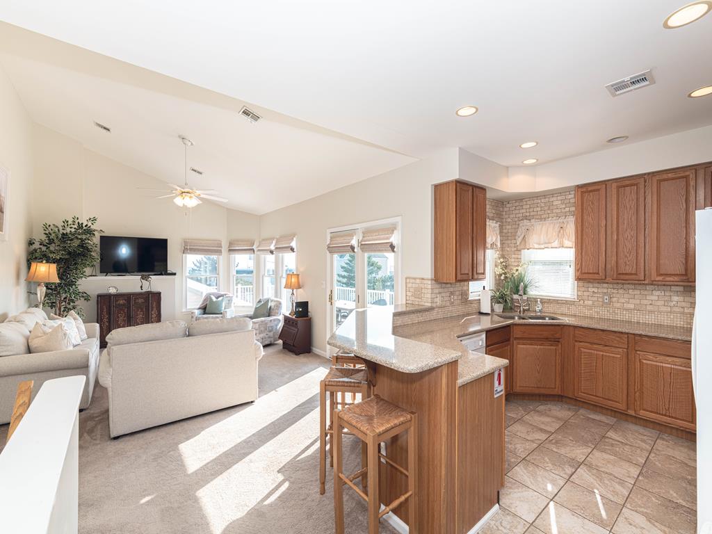 image Open kitchen and living space featuring a breakfast bar, great for casual dining or entertaining guests.