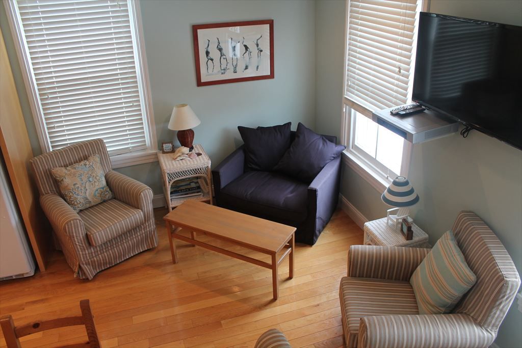 image Cozy living space with plenty of seating, natural light, and a mounted TV for entertainment.