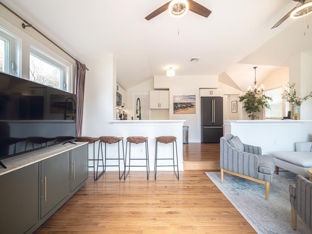 image Stylish living room featuring a flat-screen TV, hardwood floors, and an airy layout.