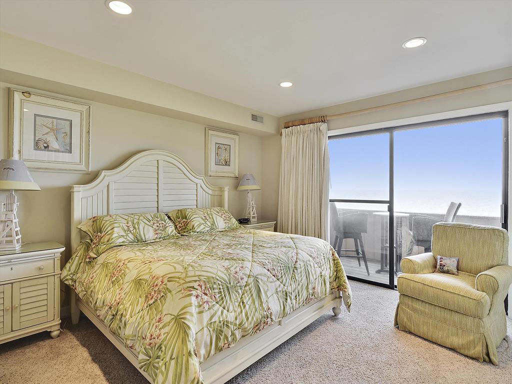 image Bright and airy oceanfront master suite featuring a comfortable bed and large windows with breathtaking views.
