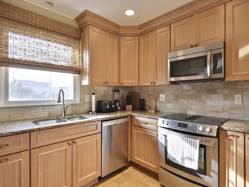 image Full kitchen featuring granite countertops, custom cabinetry, stainless steel appliances, and a peninsula for casual dining.