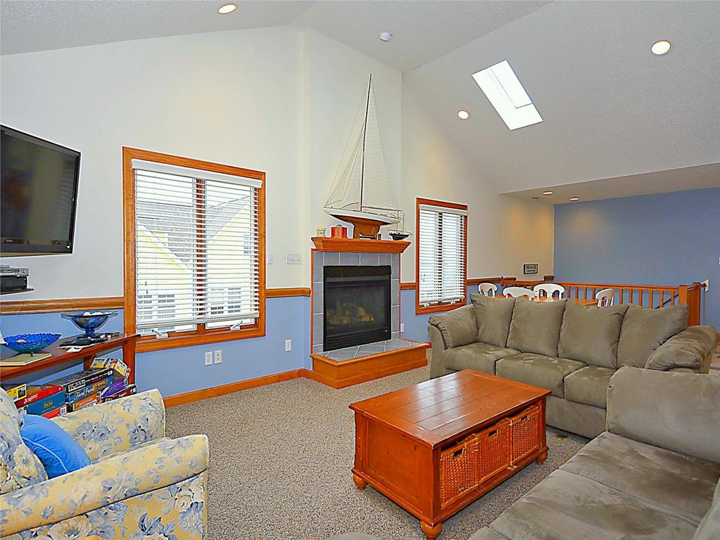 image Inviting family room with comfortable seating, a fireplace, and a vaulted ceiling, offering a cozy space to unwind.