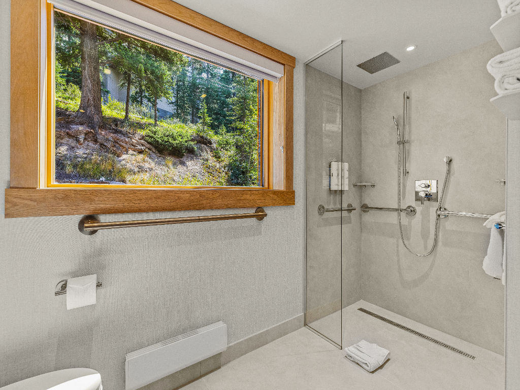 image A modern and accessible bathroom featuring elegant finishes and a window that frames lush greenery, providing a tranquil backdrop.