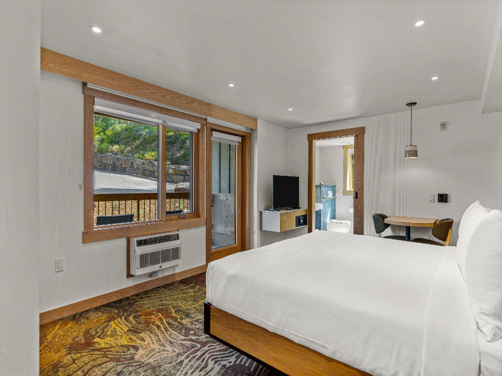 image A bright and spacious bedroom with natural light streaming through large windows, offering a peaceful retreat surrounded by nature.