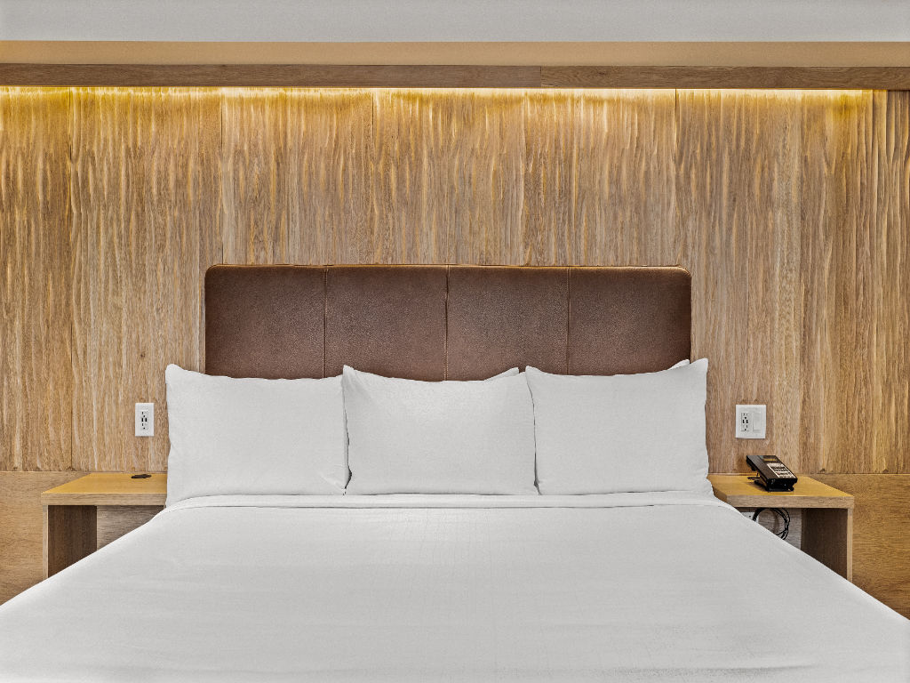 image A serene bedroom with warm lighting and a plush bed, offering a restful and inviting atmosphere for a perfect night's sleep.