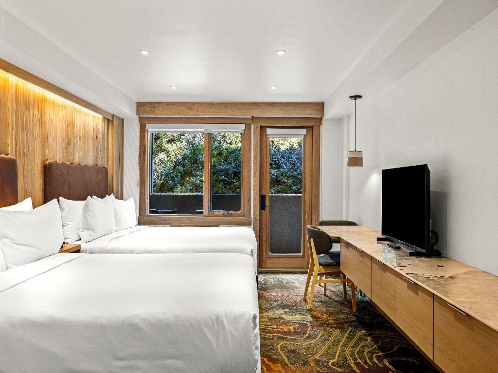 image A tranquil room featuring plush bedding, warm wooden accents, and a door leading to an outdoor space, creating a harmonious connection with nature.