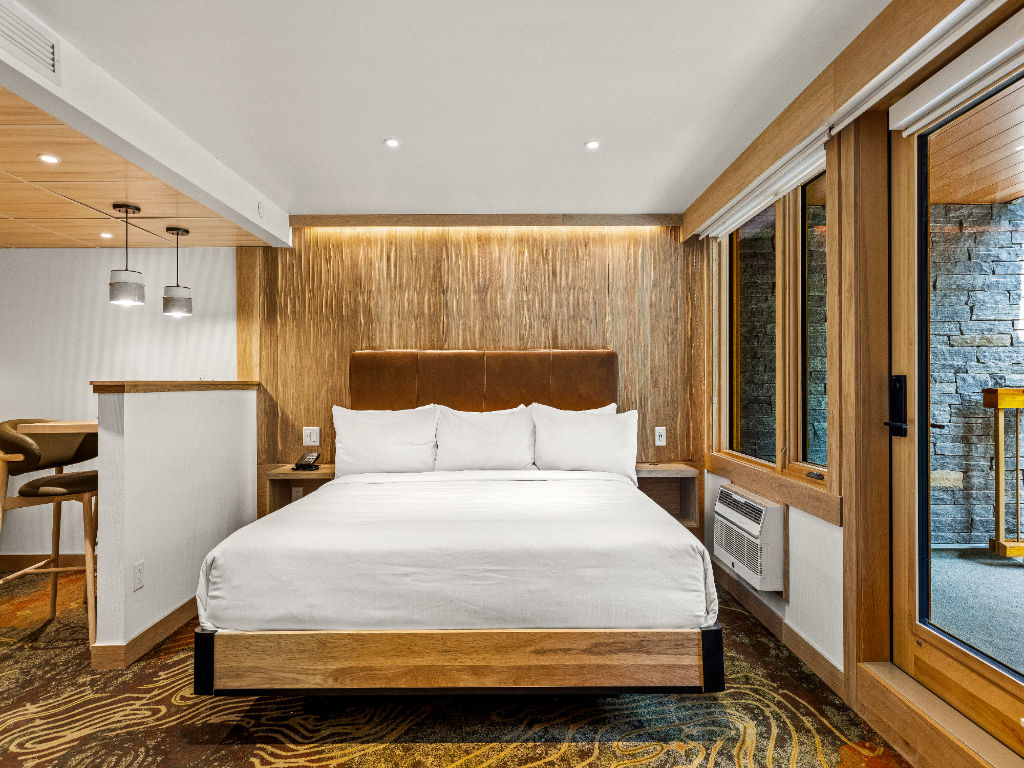 image A spacious bedroom with warm wood accents, a plush bed, and large windows, creating a harmonious and restful environment.