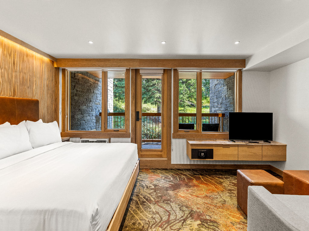 image A bright and inviting space with a large bed and doors that open to serene greenery, blending indoor comfort with outdoor beauty.