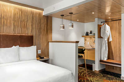 A cozy and stylish bedroom featuring a plush bed, warm wood accents, and a thoughtfully integrated wardrobe and seating nook for added convenience.