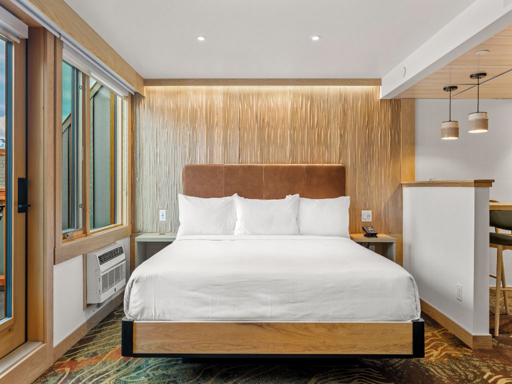 image A serene bedroom with warm wooden accents, a plush bed, and large windows for an inviting and restful atmosphere.