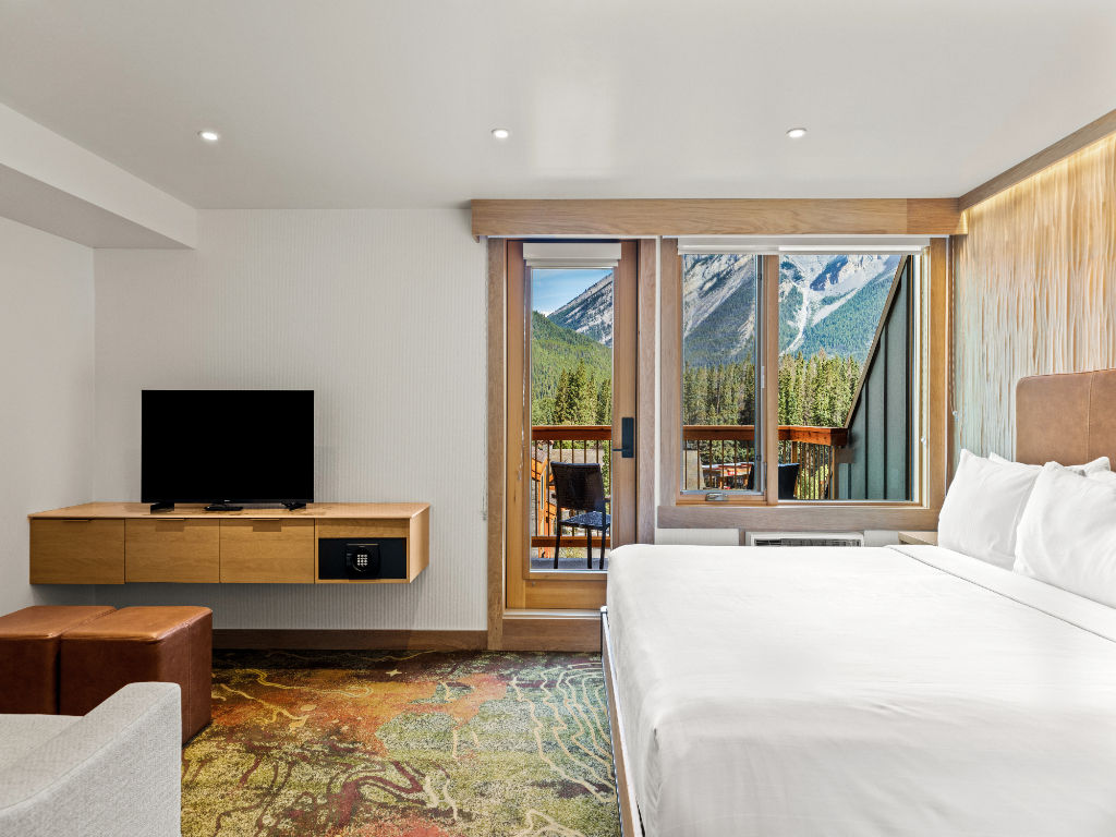image A bright and inviting bedroom with plush bedding and large windows, offering stunning views and a cozy retreat.