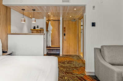 A spacious bedroom featuring warm wood tones and a seating area, perfect for relaxing in style and comfort.