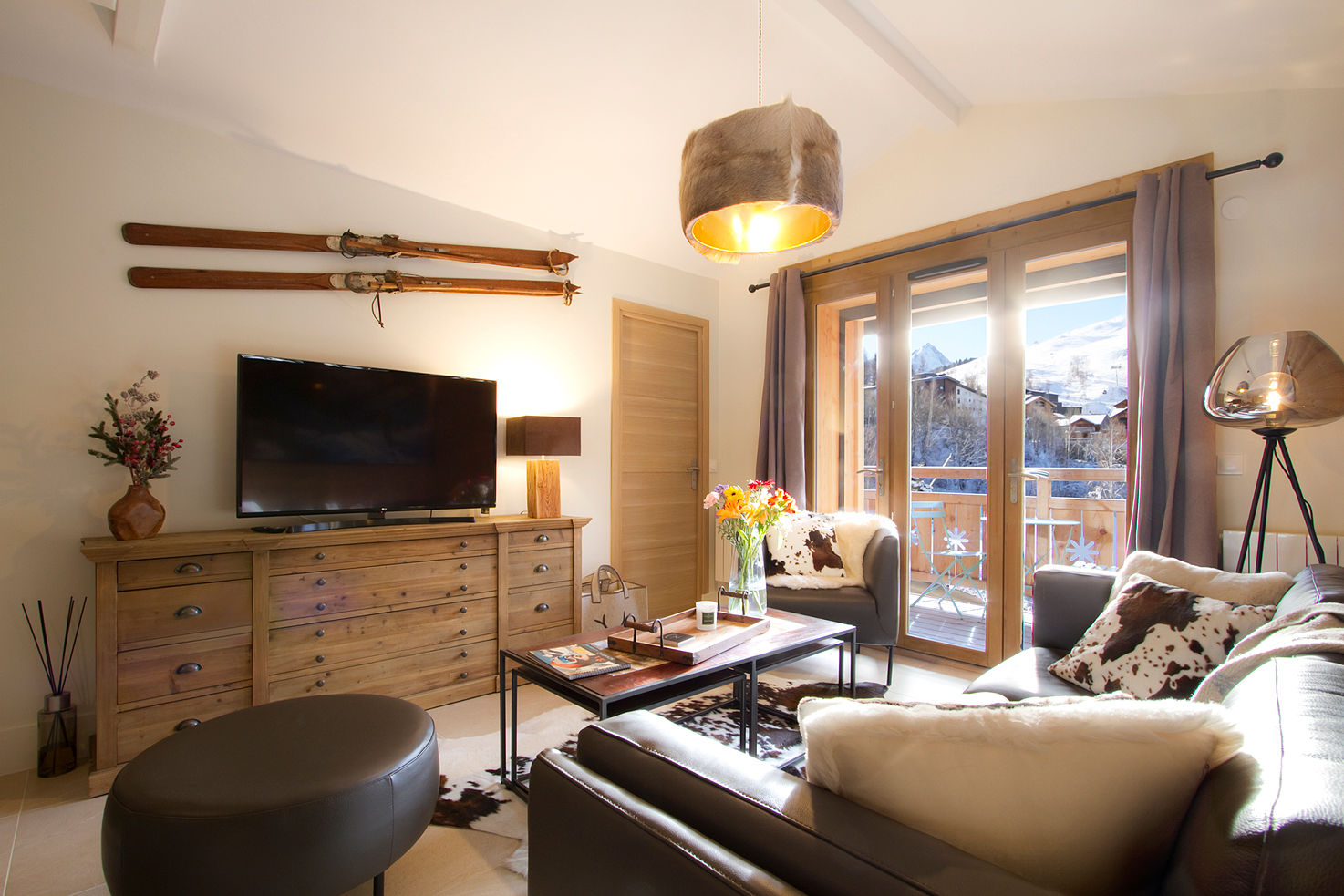 image A sunlit living area with rustic charm, cozy seating, and warm wood accents—ideal for relaxing and enjoying mountain views from the balcony.
