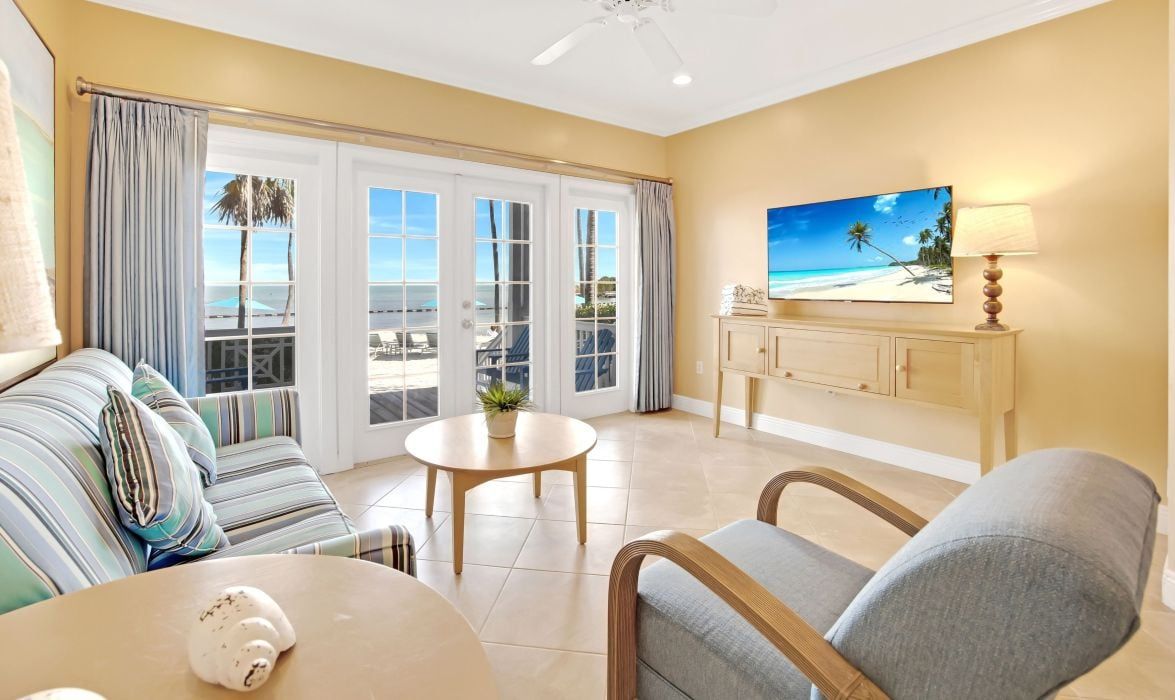 image Living room with sofa, TV, and French doors to the ocean