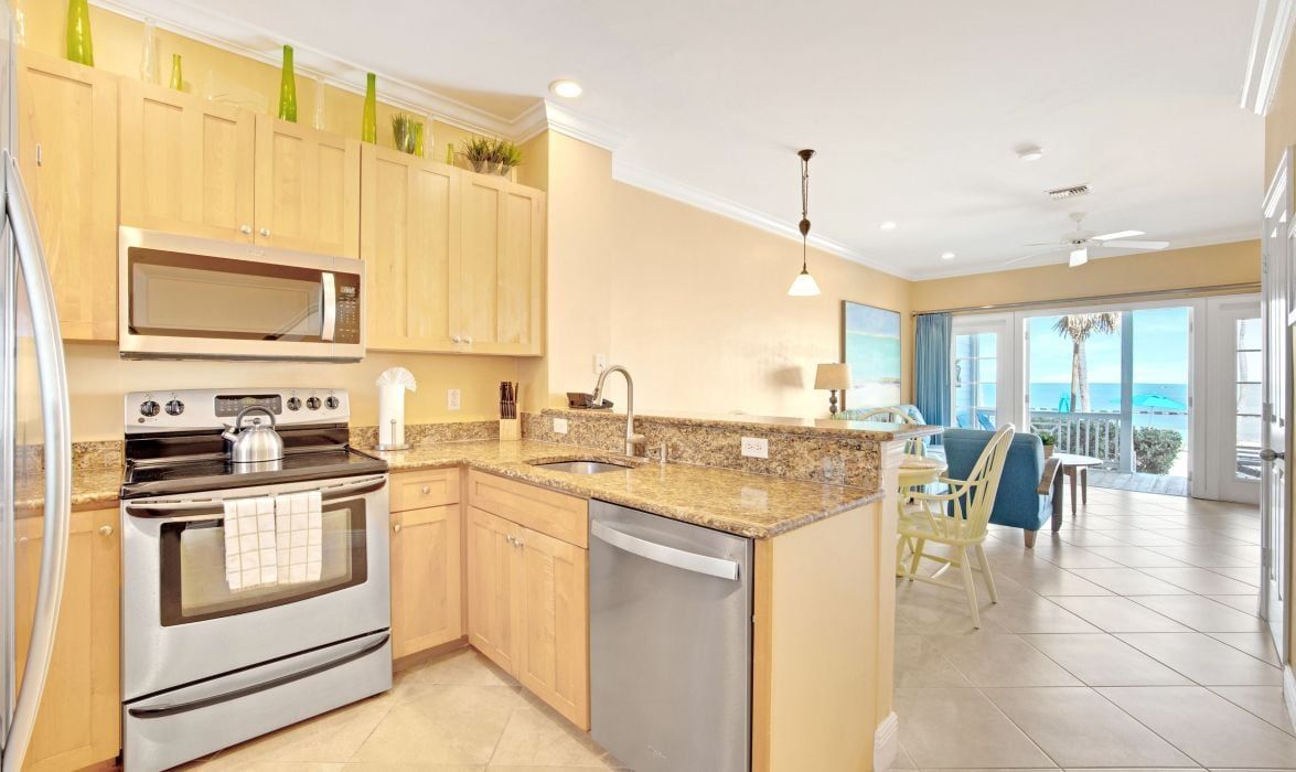 image Kitchen with wood cabinetry, stainless appliances, and ocean-view dining area