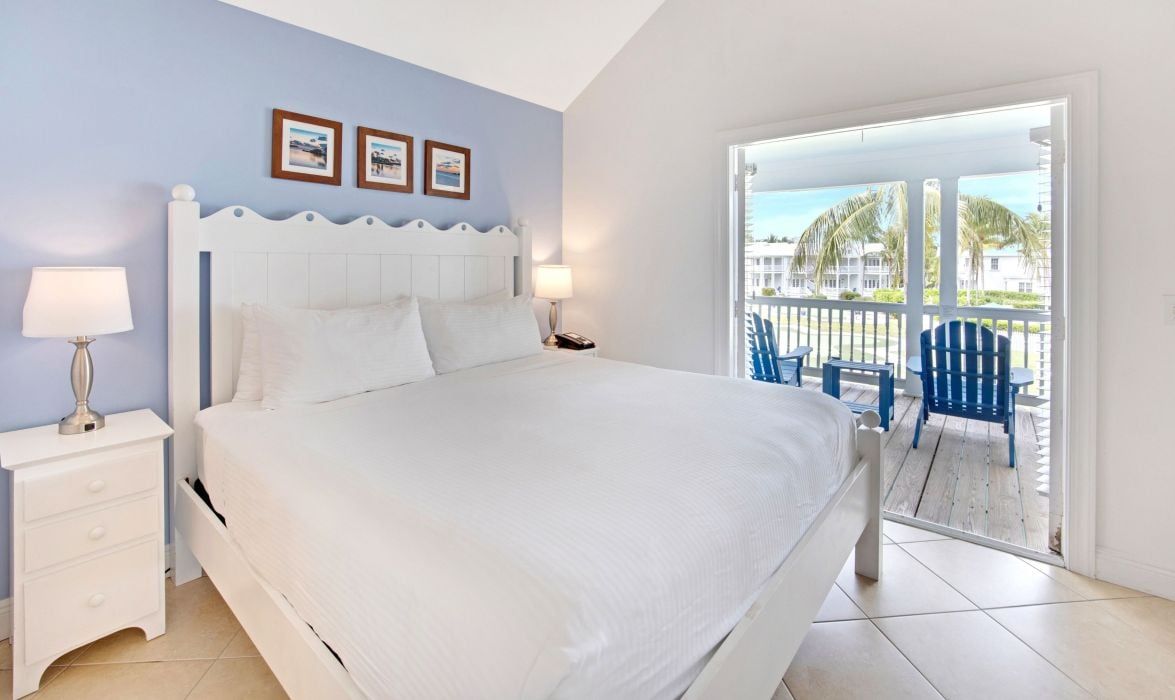 image Bedroom with white bed and porch visible through the window