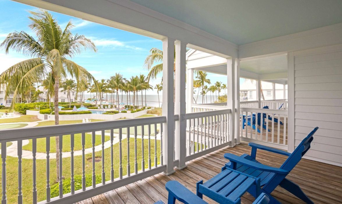 image Covered porch with blue adirondack chairs overlooking the water