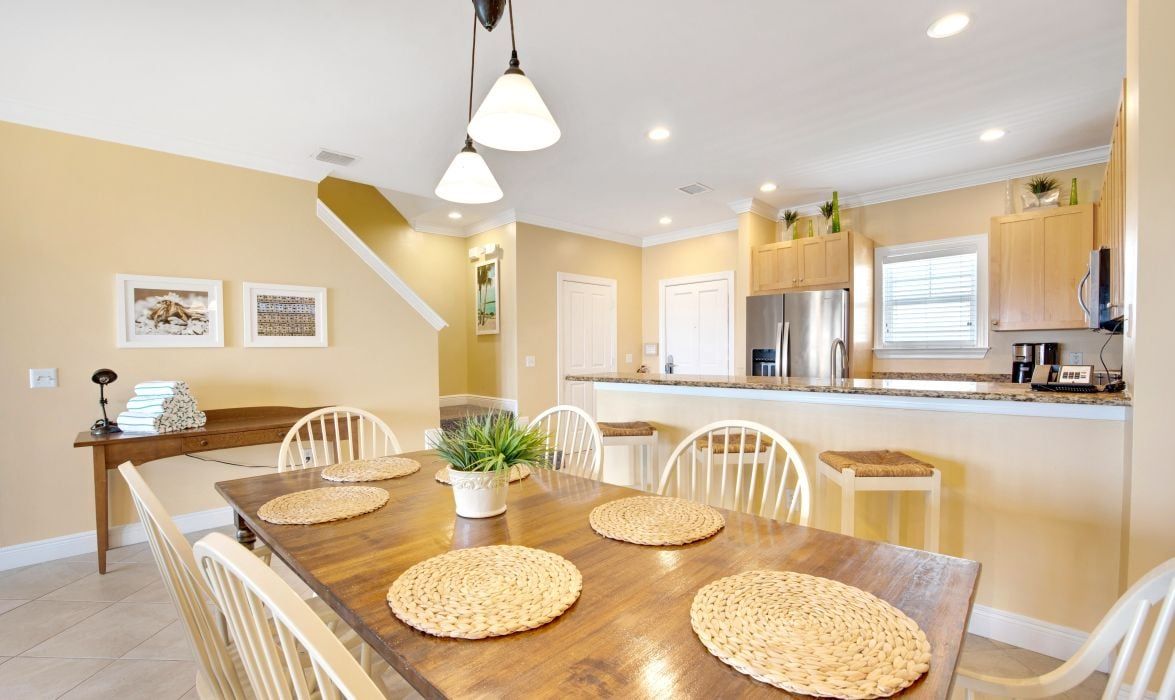 image Dining area with wood table, woven placemats, and open kitchen